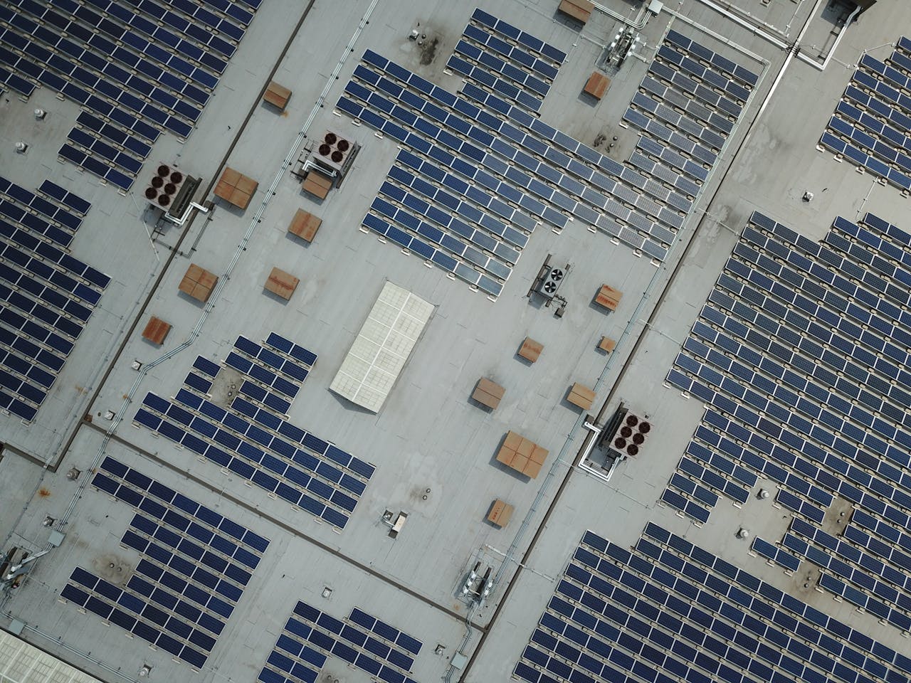 gallery-01 High-angle aerial shot of a large rooftop solar panel array on an industrial building.