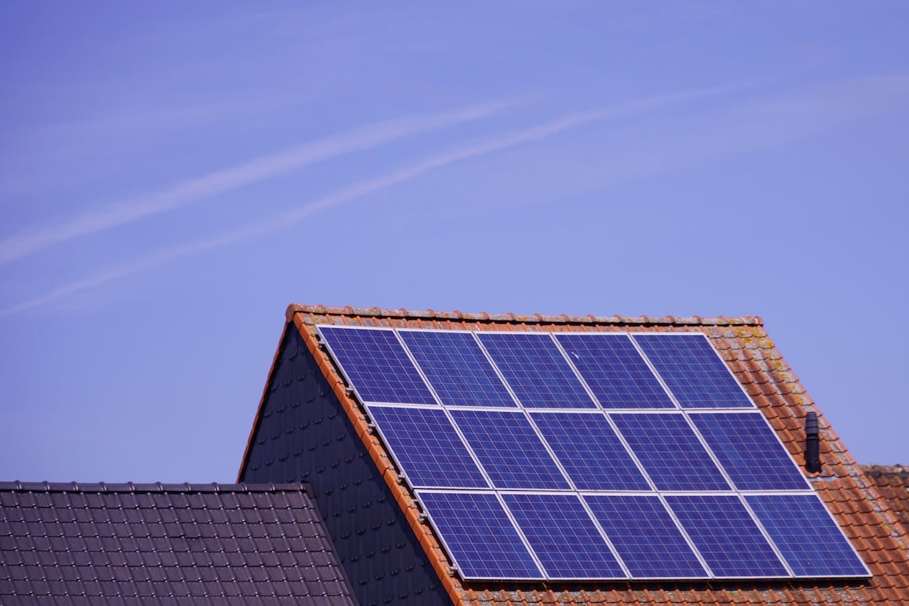 gallery-03 Close-up of solar panels on a tiled rooftop under a clear sky, showcasing renewable energy.